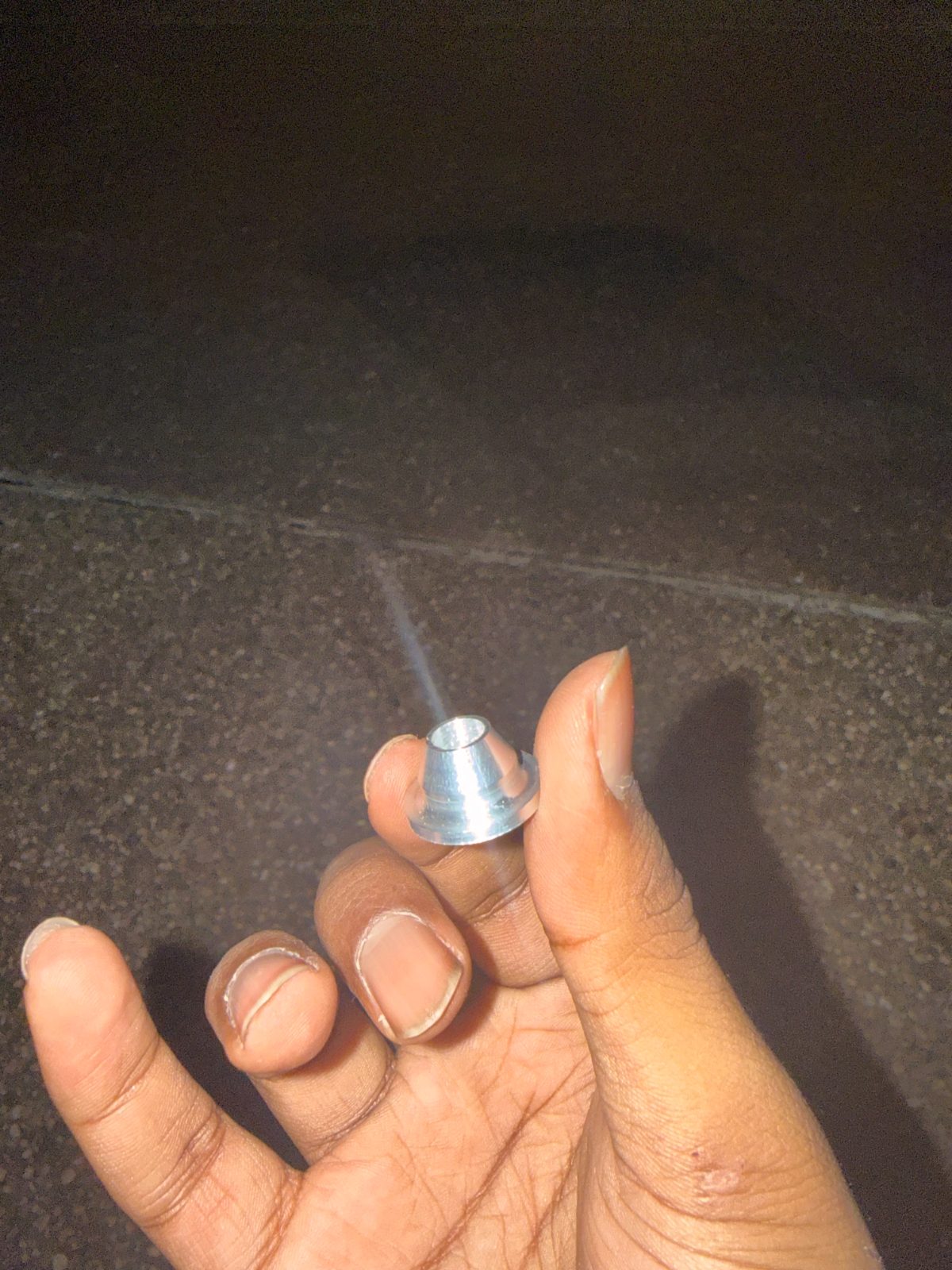Small turned aluminum part held between fingers